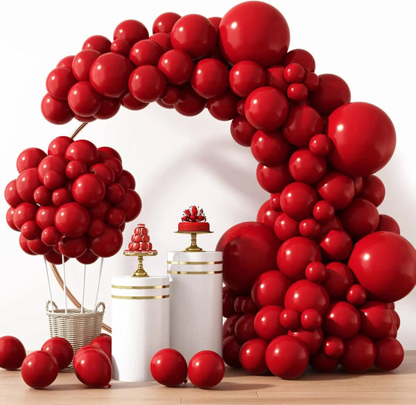 A large arch made of ruby red balloons for weddings and parties, displayed on a wooden surface.