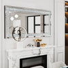 A silver crystal rhinestone wall mirror with a sparkling frame displayed above a white marble fireplace mantel.