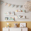 A set of two wavy wooden floating shelves mounted on a wall above a white cabinet.