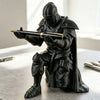 A dark, 3D printed medieval knight figure holding a pen, displayed on a gray surface.