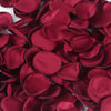 Deep red silk rose petals scattered on a white background for weddings and events