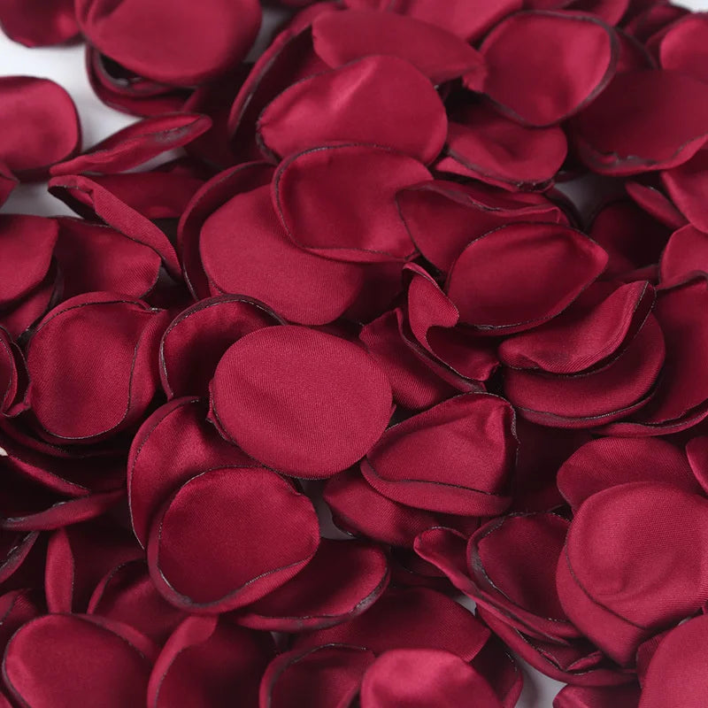 Deep red silk rose petals scattered on a white background for weddings and events