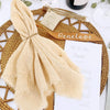 A light beige handcrafted cotton napkin tied into a bow resting on a woven placemat with a menu card.