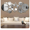 A wall decor set featuring various sized circular acrylic mirrors mounted on a beige wall above a modern sofa.