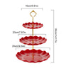 A two-tier serving stand with red ceramic plates for desserts and fruit.