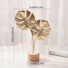 A gold-colored iron ginkgo leaf ornament set with a wooden base, shown against a white background.