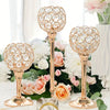 A set of golden crystal candle holders with floral designs arranged on a white table surrounded by pink and white roses.