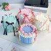 A display of four decorative fake cakes in pink, blue, and white frosting with ribbons on a white surface.