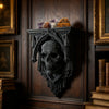 An ornate black Gothic wall shelf featuring intricate carvings and holding three colorful stones.