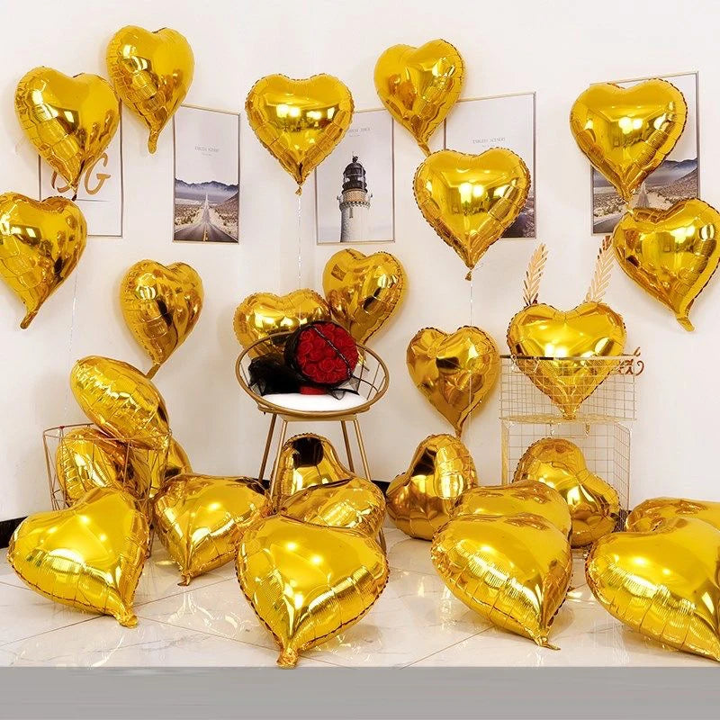 A collection of gold heart foil balloons arranged on a white background.