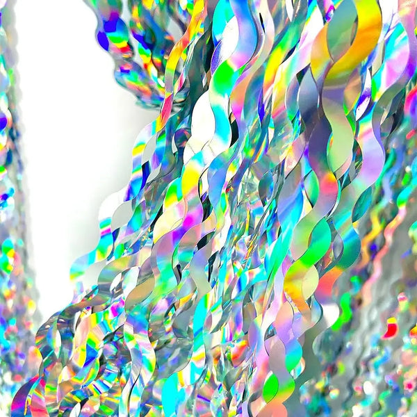 Iridescent wavy foil fringe curtain fabric showing vibrant rainbow colors and shimmering texture.