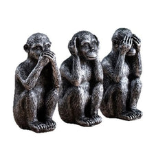 A set of three resin figurines depicting the Three Wise Monkeys looking at their hands.