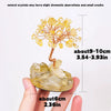 A hand holds a natural crystal tree featuring yellow crystals and small cracks, used for home or office decor.