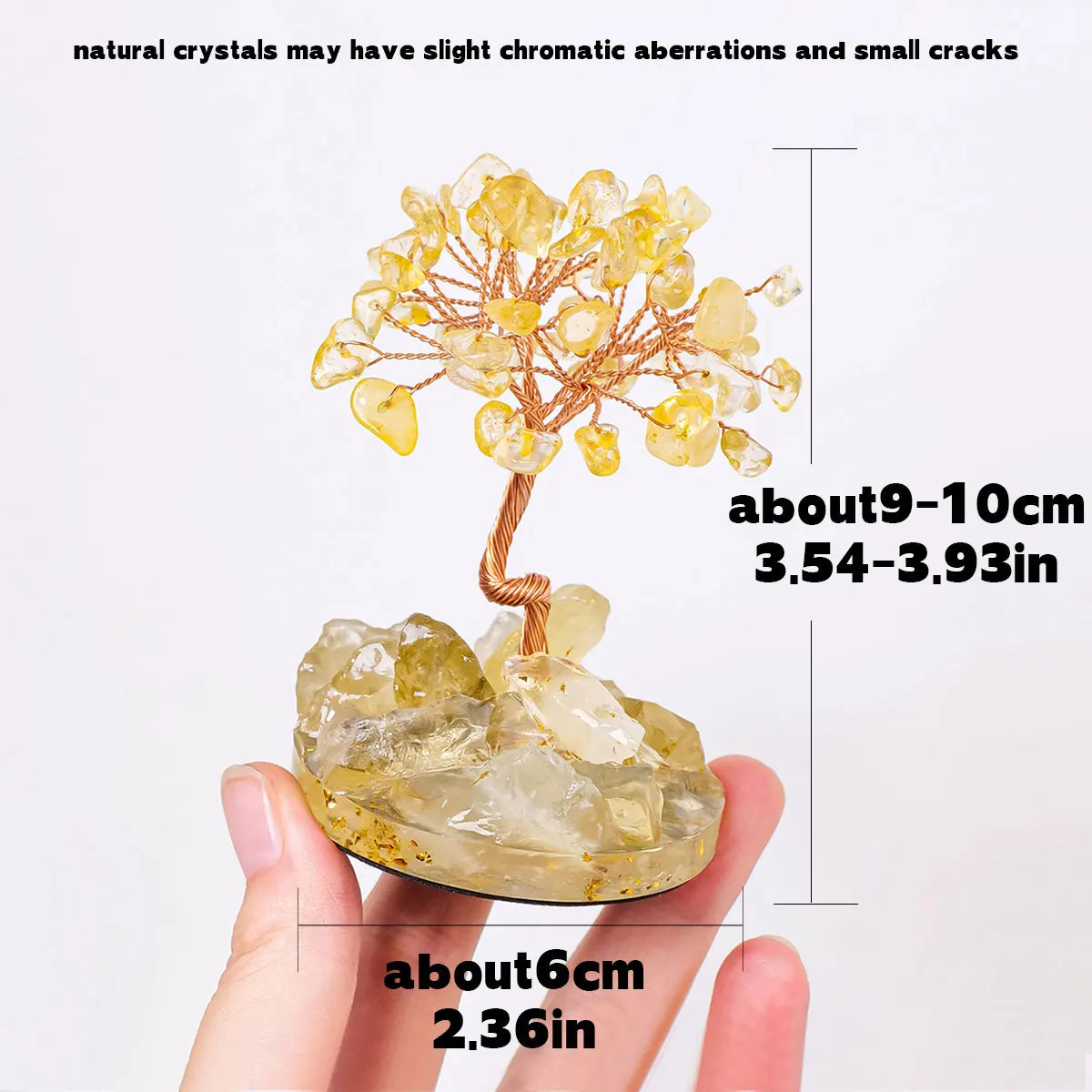 A hand holds a natural crystal tree featuring yellow crystals and small cracks, used for home or office decor.