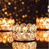 A close-up of a crystal tealight candle holder with a metal base surrounded by glowing candles.