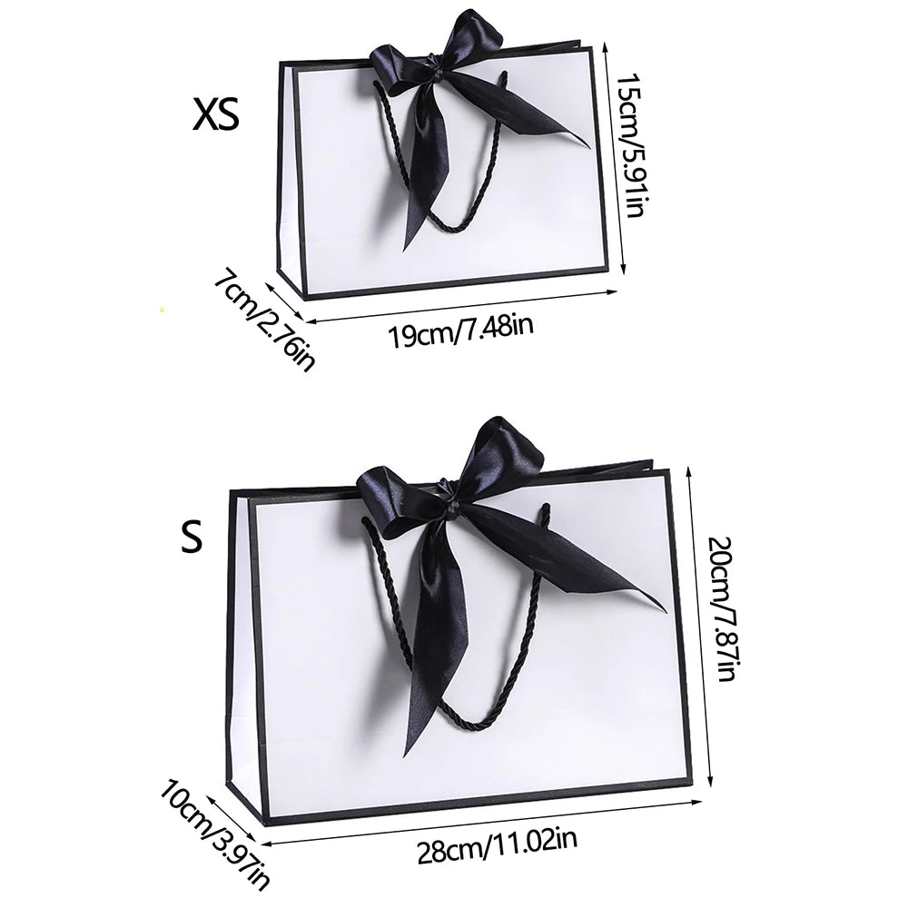 A set of elegant black and white gift bags with black ribbon bows shown in small and medium sizes.