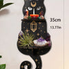 A black cat silhouette floating shelf featuring a moon, candle, and crystals on a dark background.