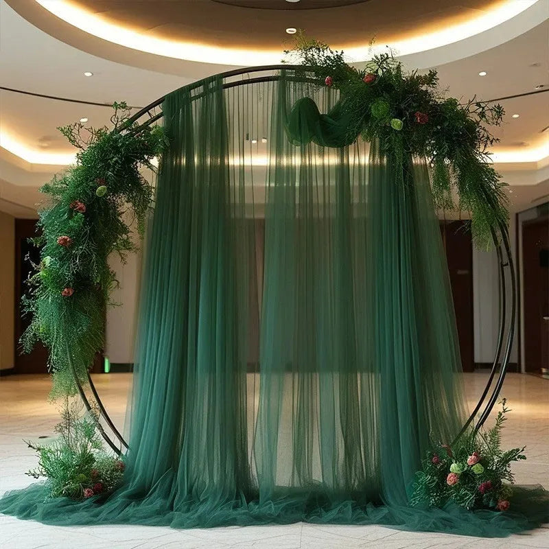 Tela verde transparente y elegante que cae formando un fondo arqueado para un evento.