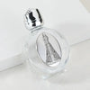 A clear glass bottle with a silver figurine inside and a twist cap resting on a white surface.