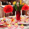 Un ensemble de bougies parfumées en forme de cœur disposées sur une table avec des décorations florales et des accents rouges