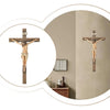 A hand-painted resin cross statue with a figure of Jesus Christ is displayed on a wall.