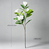 A tall artificial magnolia tree with white silk flowers and green leaves shown against a gray background.