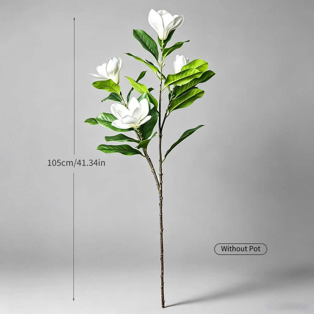 A tall artificial magnolia tree with white silk flowers and green leaves shown against a gray background.