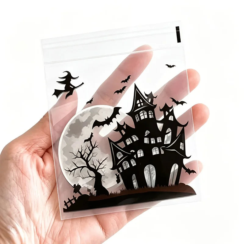 A hand holds a clear self-adhesive treat bag featuring a silhouette of a spooky castle and bats against a full moon backgroun