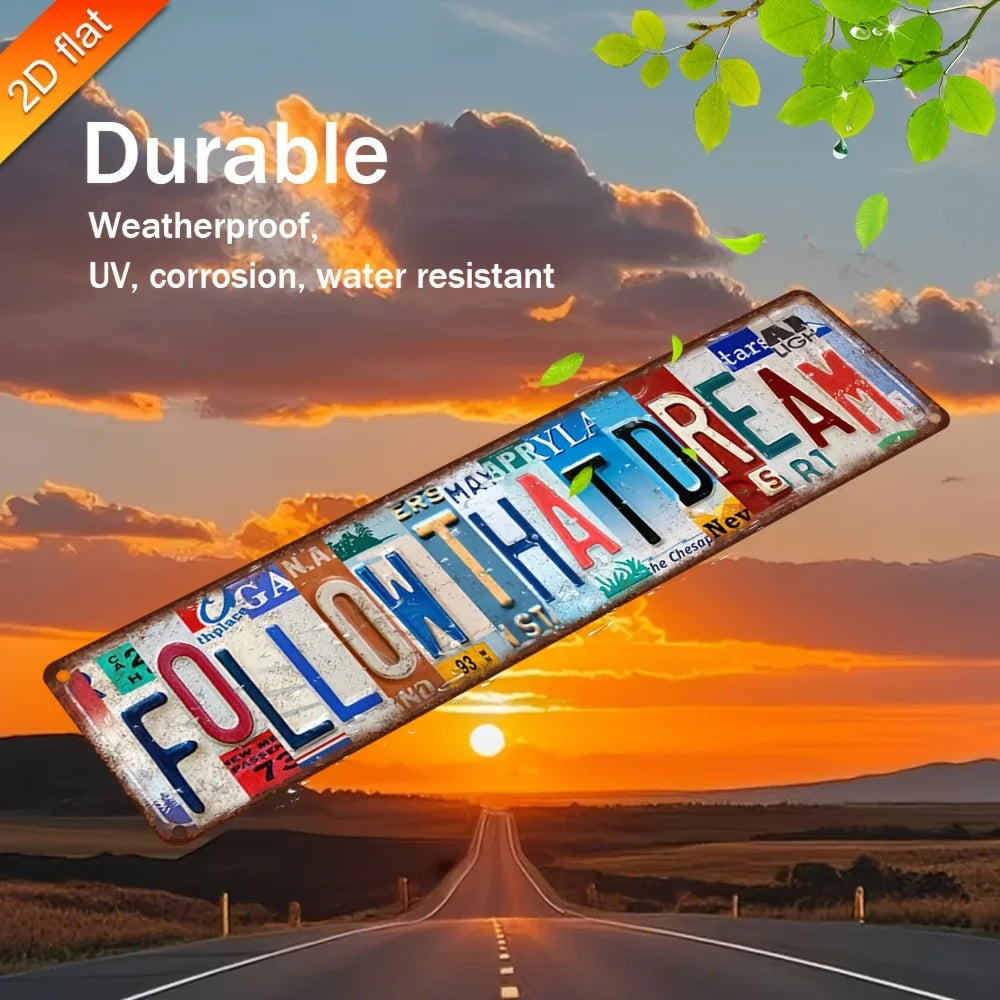A vintage aluminum metal wall art sign with the text FOLLOW THAT DREAM is displayed against a sunset road backdrop.