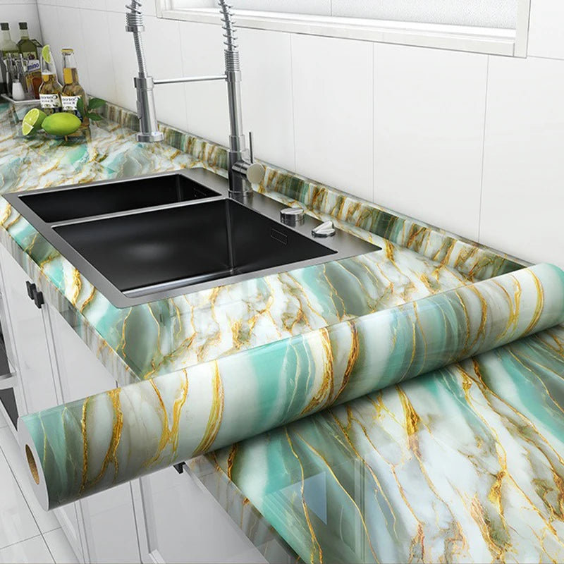 A roll of marble self-adhesive wallpaper featuring green and gold veining used as a countertop surface.