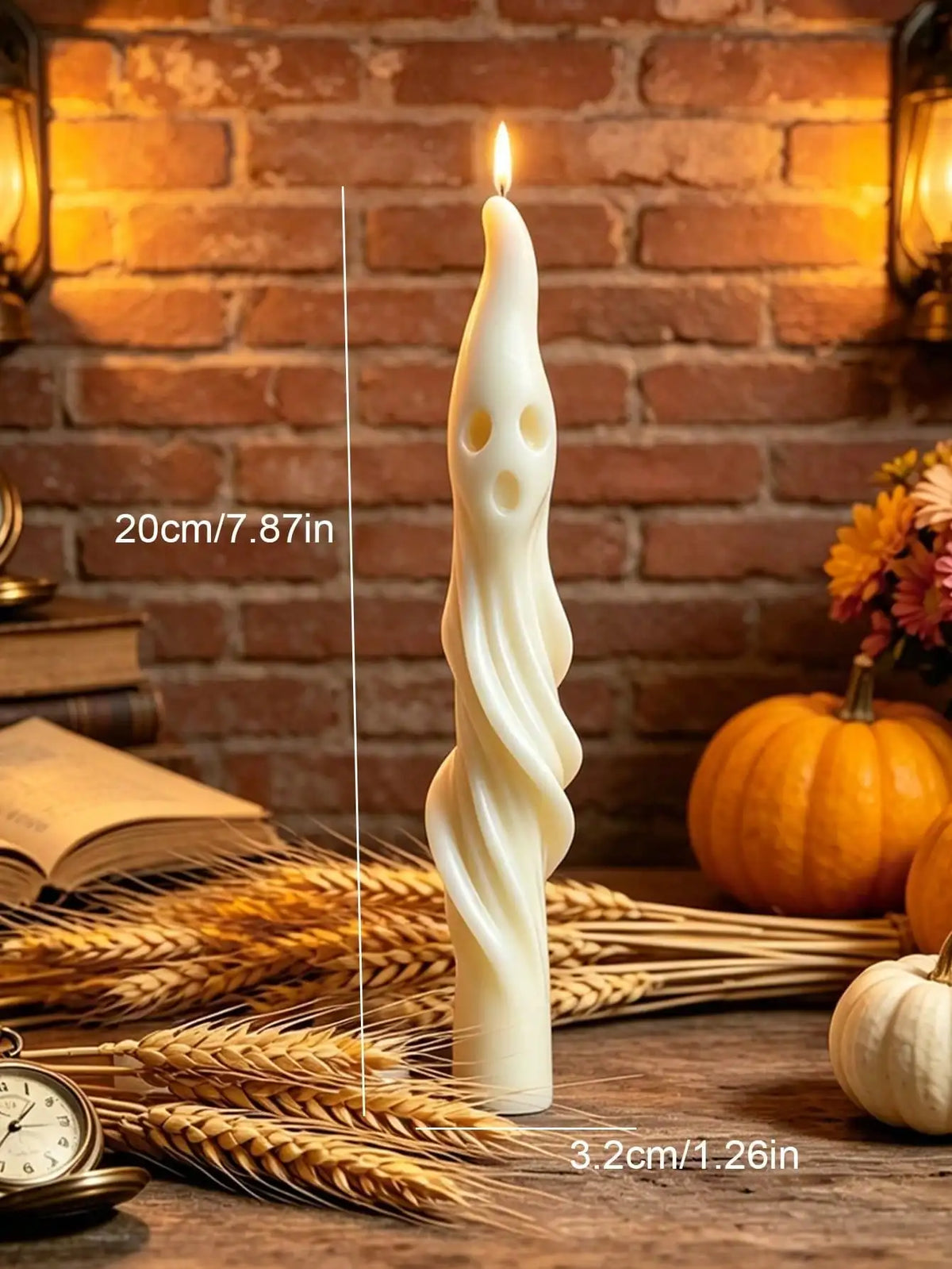 A tall white candle shaped like a mummy or ghost stands on straw and wheat stalks against a brick background.
