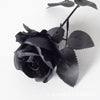 A dark black velvet artificial rose with a bendable stem on a white background.