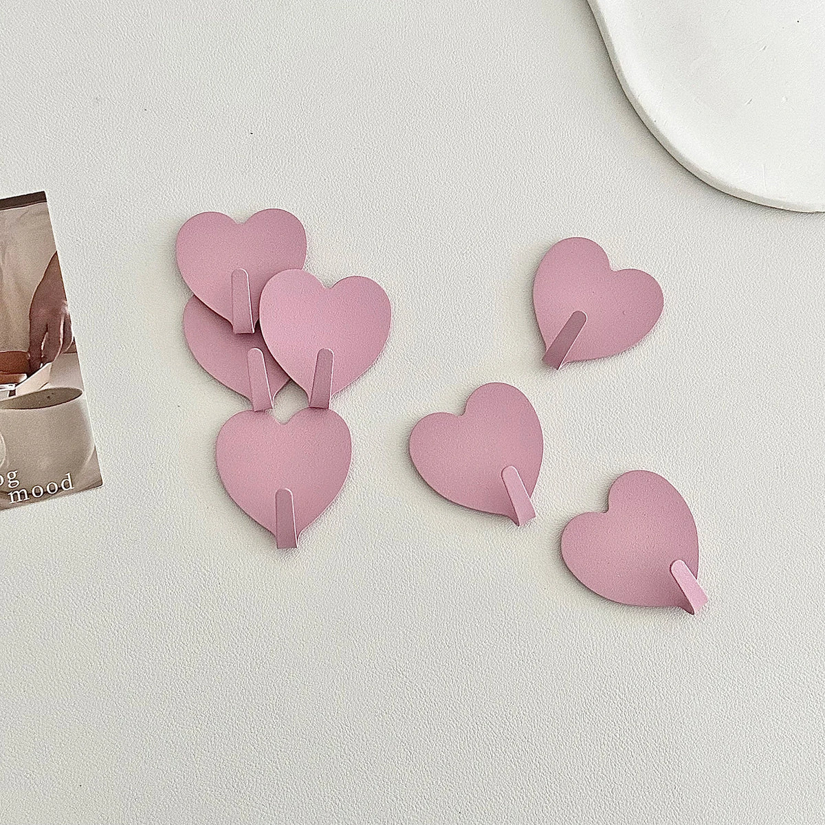 A set of pink heart-shaped adhesive hooks for various rooms, displayed on a white surface.