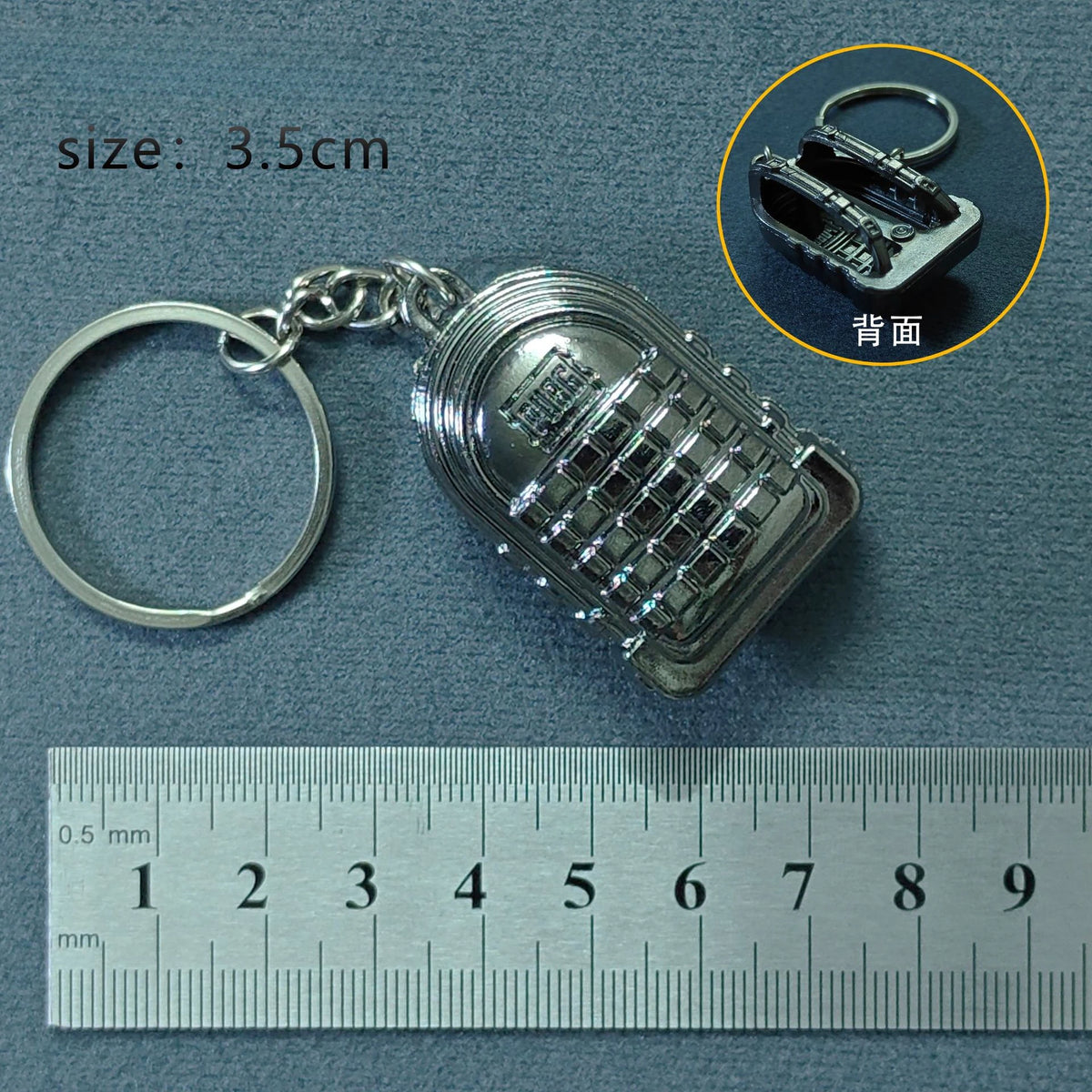 Silver alloy gun model keychain with a textured surface and a keyring, shown next to a ruler.
