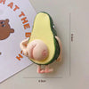 A yellow avocado shaped magnet with a green rind and a pink fruit interior, shown next to a ruler.