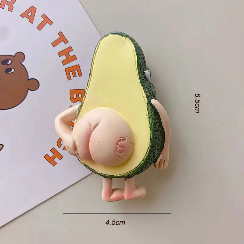 A yellow avocado shaped magnet with a green rind and a pink fruit interior, shown next to a ruler.