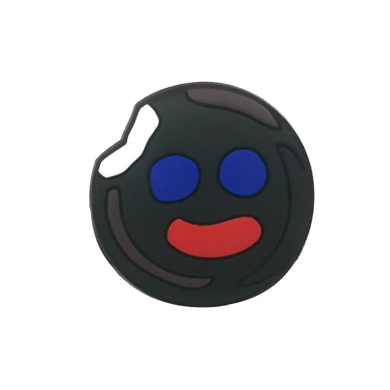 A black PVC shoe charm shaped like a smiling face with blue eyes and a red mouth.