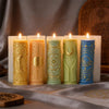 A row of nine pillar candles in various pastel colors featuring celestial and mystical symbols