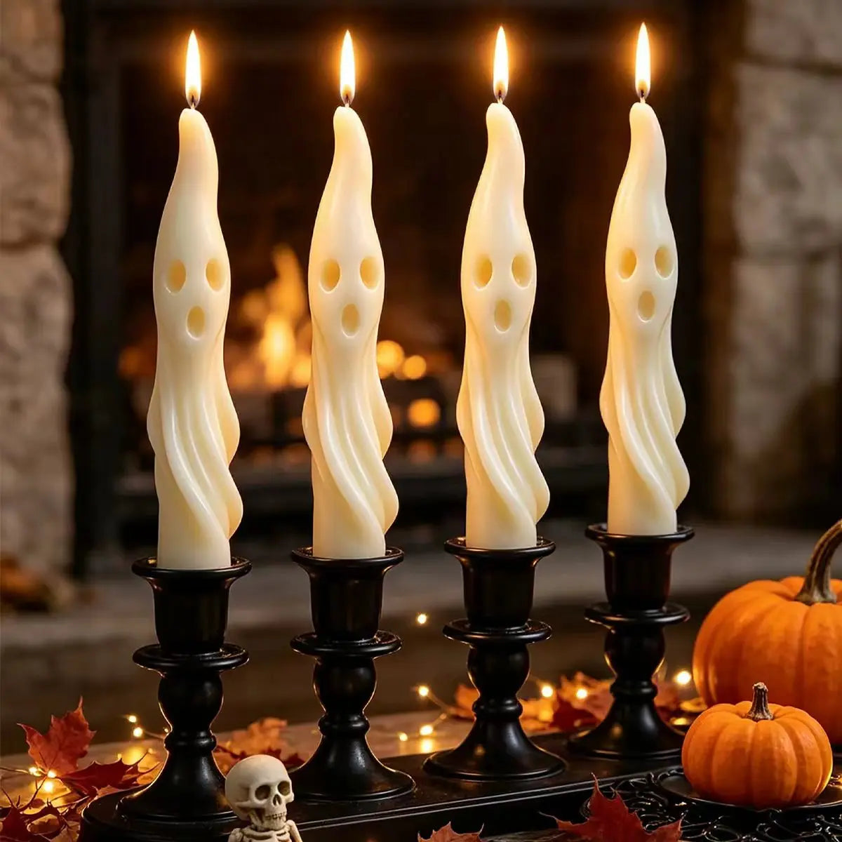 A set of four white soy candles shaped like ghosts and mummies displayed on a dark surface with autumn leaves.