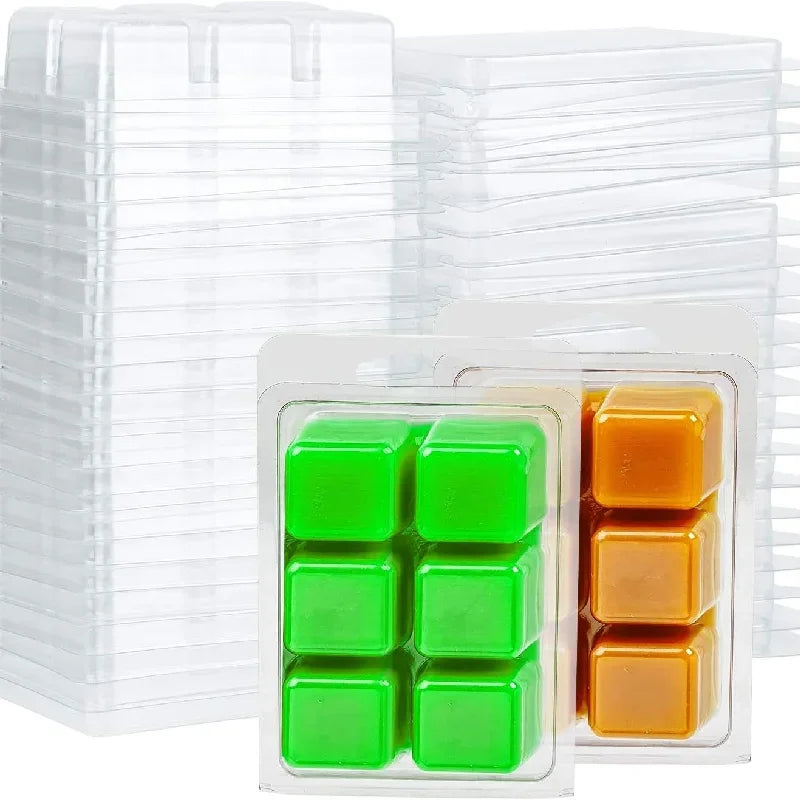 A stack of clear plastic clamshell molds containing small green and orange wax melts.
