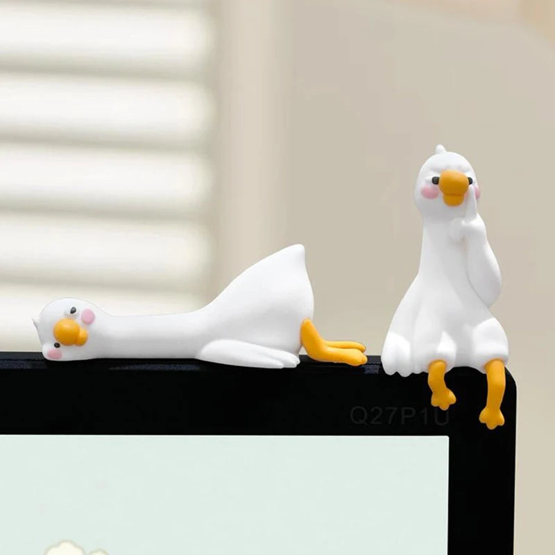 Figurine de canard en résine blanc et jaune, décorative, posée sur une surface noire.