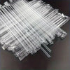 A pile of clear disposable plastic straws arranged diagonally on a dark surface.