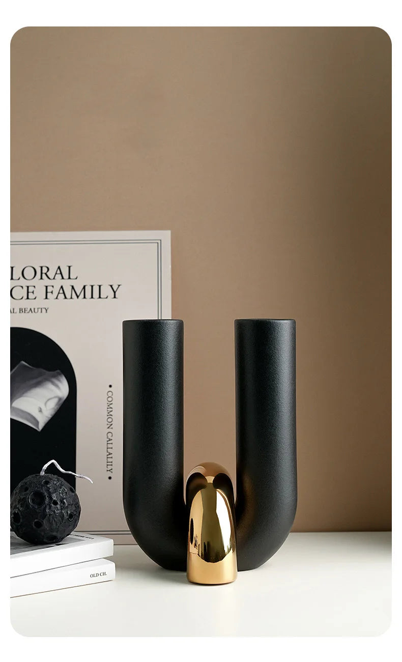 A set of matte black U-shaped ceramic tabletop vases displayed on a white surface.