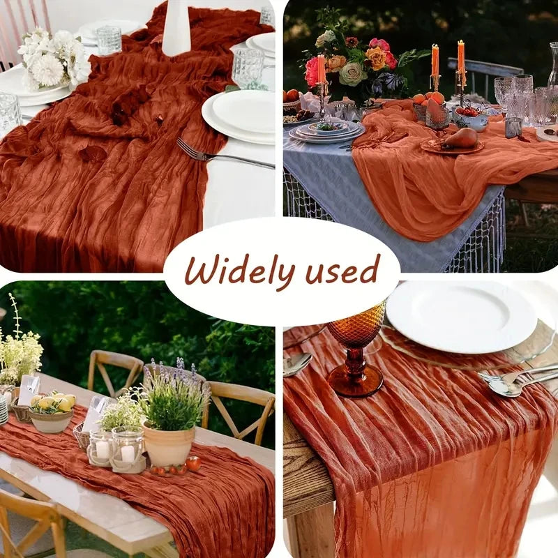 A rust orange boho style cheesecloth table runner draped over a wooden table in an outdoor setting.