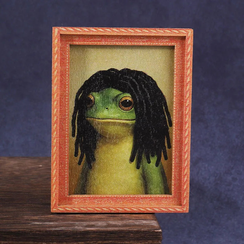 A cute green frog character is displayed inside a wooden photo frame.
