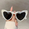 A pair of heart-shaped sunglasses decorated with white pearls and the words just married