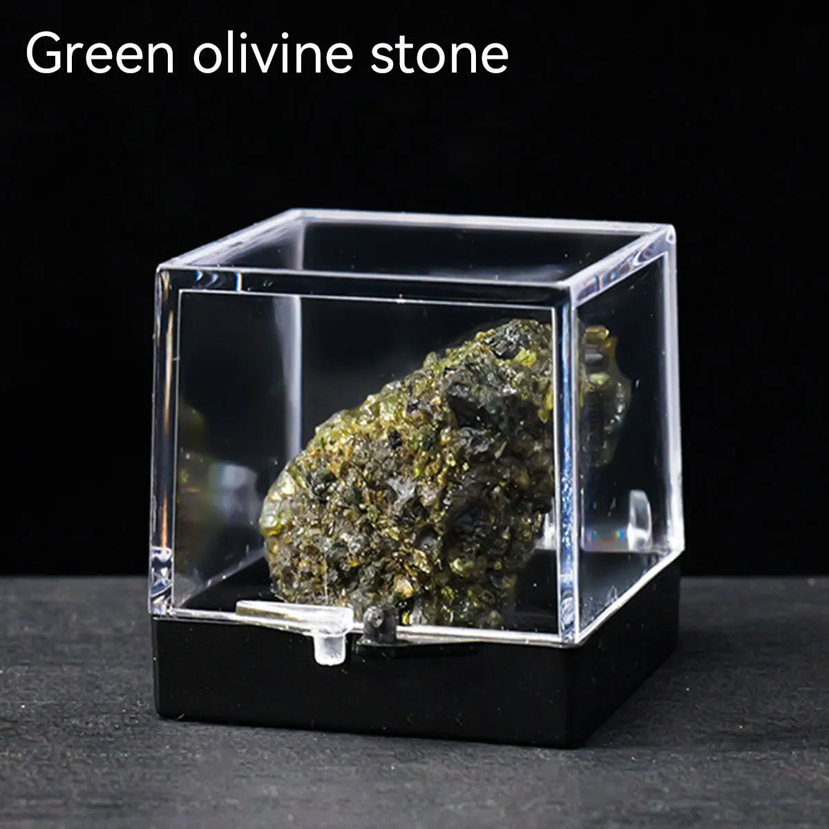 A rough green olivine stone specimen displayed inside a clear glass box.