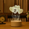 A white acrylic LED night light shaped like three overlapping hearts on a wooden surface.