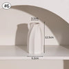 A white minimalist ceramic vase is displayed on a shelf, shown from the side with dimensions provided.