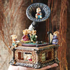 A vintage carousel music box decoration featuring a small bear figurine on a dark metal stand.